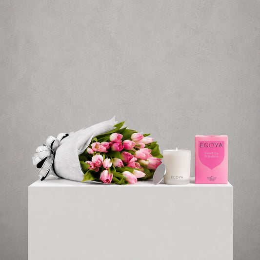 Bouquet of pink flowers, white candle, and pink box labeled 'ECOYA' on a gray background